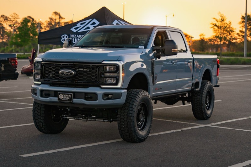 Lifted heavy-duty Ford pickup parked at sunset.