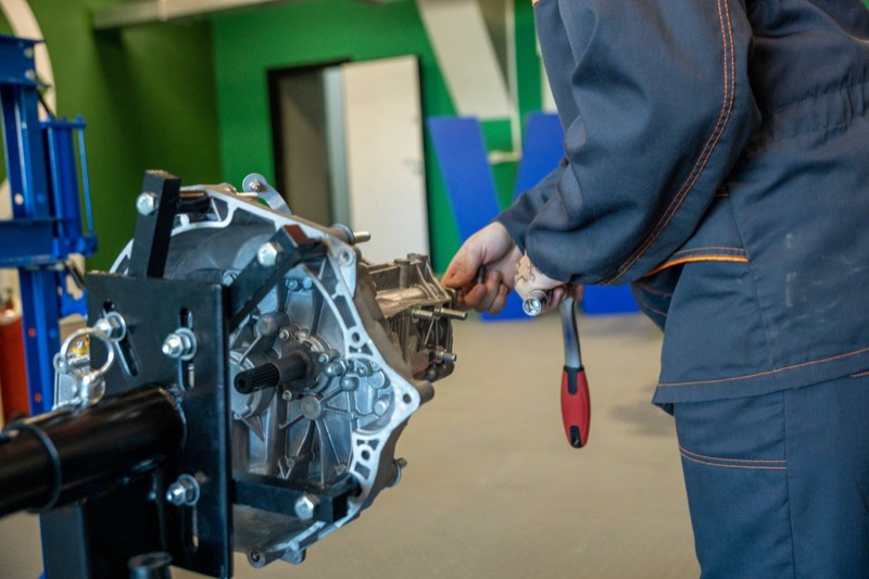 Mechanic working on a transmission mounted on a stand.